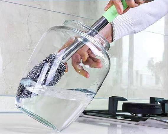 Hand holding a Bottle Jar Toilet Cleaner Brush Scrubber submerged in water, showcasing its cleaning capabilities.